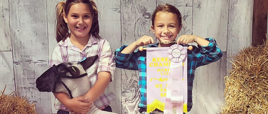 two young girls showing their awards won and lamb for the youth market